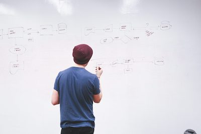 young man drafting schematics on white board