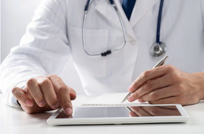Doctor wearing lab coat and stethoscope using tablet and stylus to chart