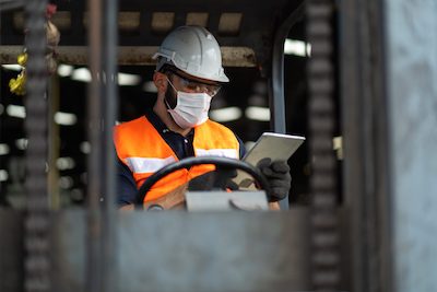 Trades worker on machine using tablet